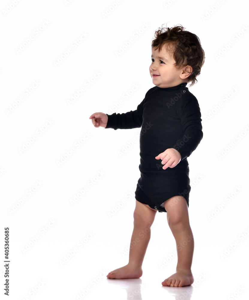 First steps of toddler toddler baby in black bodysuit isolated on white First steps of toddler toddler baby in black bodysuit isolated on white