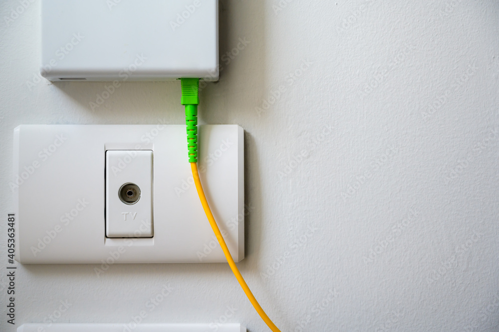 TV socket available on the white wall under fiber optic internet wall box.  Stock Photo | Adobe Stock