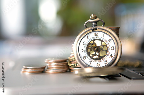 A row of dollar coins and a pocket watch on a computer keyboard