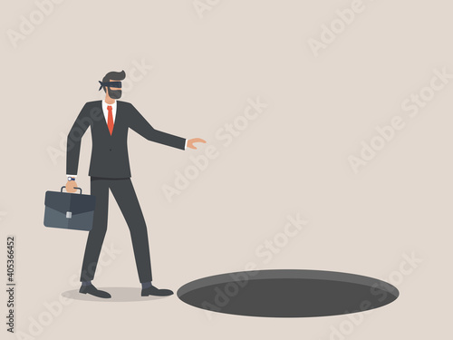 Businessman using a blindfold walks into a hole or trap