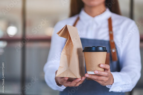 Foto A waitress holding and serving paper cup of coffee and takeaway food in paper ba