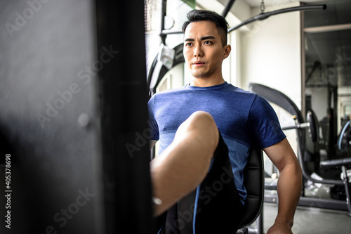 Asian young man doing leg presses in gym © Tom Wang