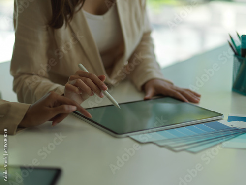Female hands working with digital tablet and supplies on the table