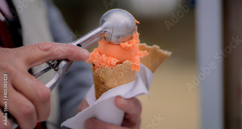 Saleswoman in an ice cream parlor takes a drop of ice cream