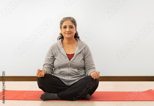 A SENIOR ADULT WOMAN SITTING AND MEDITATING 