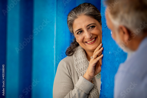 AN ADULT WOMAN LOVINGLY LOOKING AT HUSBAND WHILE STANDING BEHIND A WALL 
