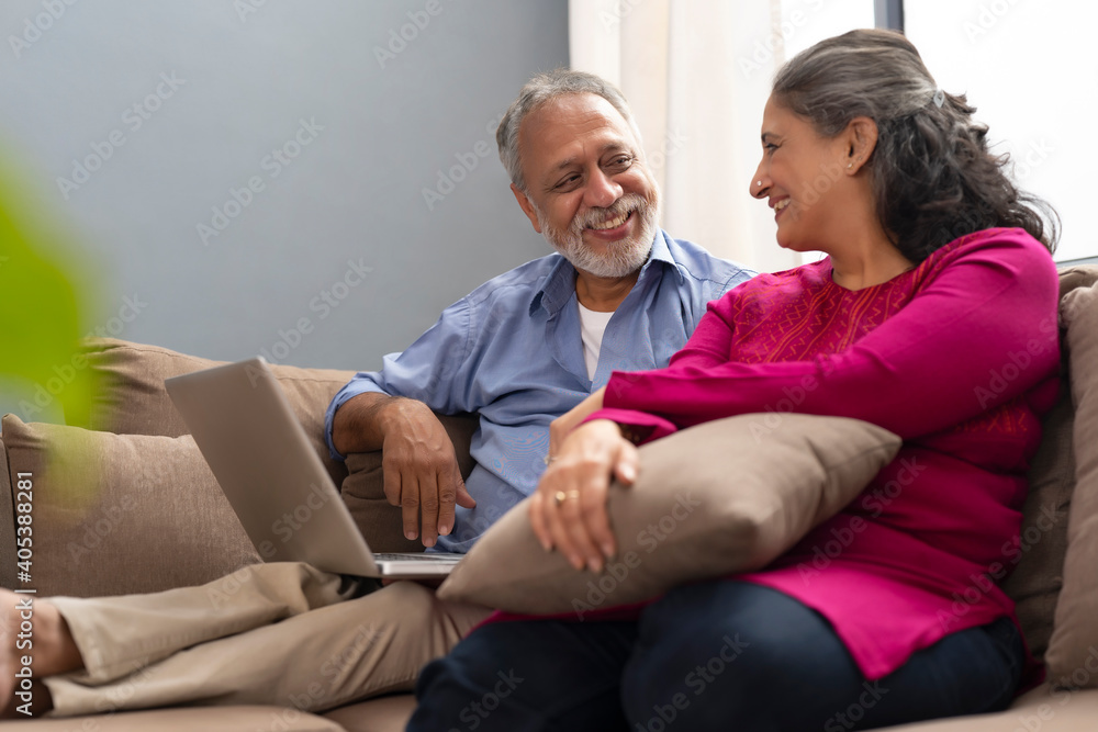 A HAPPY OLD COUPLE LOOKING AT EACH OTHER WHILE SITTING WITH LAPTOP A HAPPY OLD COUPLE LOOKING AT EACH OTHER WHILE SITTING WITH LAPTOP