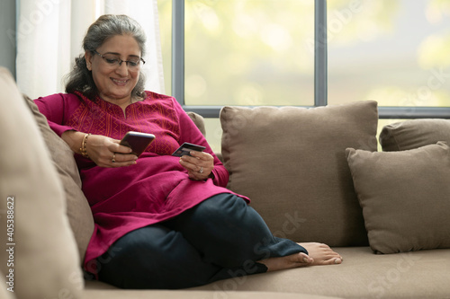 Wall Mural A SENIOR ADULT WOMAN HOLDING DEBIT CARD AND MOBILE PHONE TO DO ONLINE TRANSACTIO