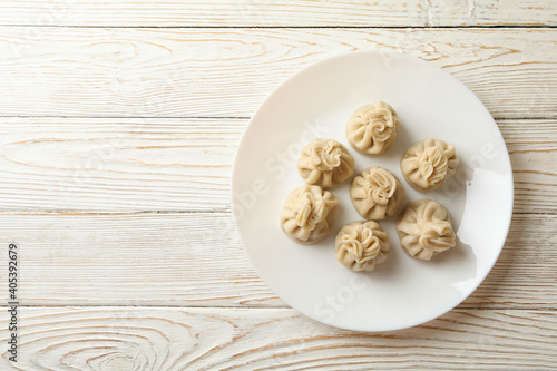 Plate with tasty khinkali on wooden background