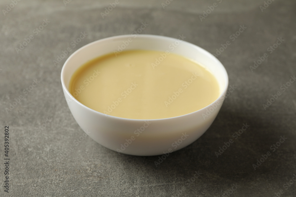 Bowl with condensed milk on gray background Bowl with condensed milk on gray background