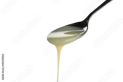 Spoon with dripping condensed milk isolated on white background