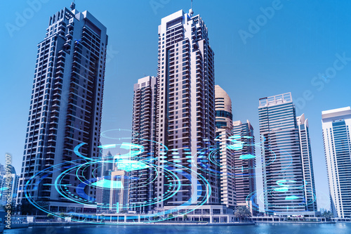 Skyscrapers of Dubai business downtown. International hub of trading and financial services. Technology theme icons hologram  Fintech concept. Double exposure. Dubai Canal waterfront.