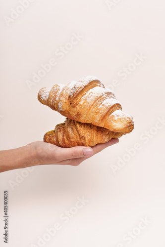 The woman hand has hold croissants and the beige background 