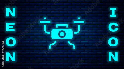 Glowing neon Drone flying icon isolated on brick wall background. Quadrocopter with video and photo camera symbol. Vector.