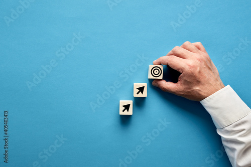 Canvas Print Arrow and target symbols on wooden blocks with a businessman hand placing the target symbol