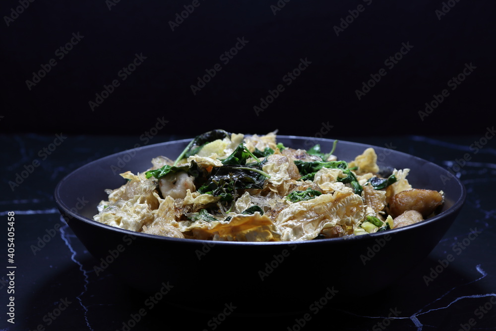 Fried and stirred spicy fresh vermicelli with tofu sheet, chilly and basil serving on the plate. Famous vegetarian menu in Asia restaurant. Fried and stirred spicy fresh vermicelli with tofu sheet, chilly and basil serving on the plate. Famous vegetarian menu in Asia restaurant.