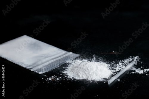 ketamine drugs and plastic straw on bag of white powder on black wood background.Drug epidemic concept.