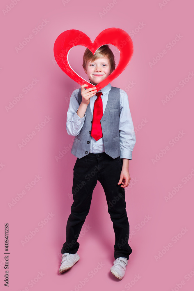 Valentines day. Smiling stylish little boy posing with heart on pink background Valentines day. Smiling stylish little boy posing with heart on pink background