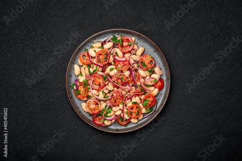 A Piyaz salad on black plate on dark slate table top. Turkish cuisine vegetarian dish. Middle eastern cuisine food. Top view