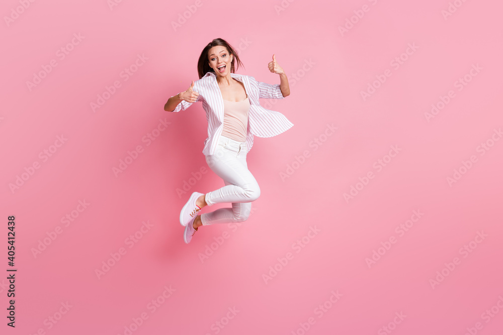 Full length photo of lovely funny young lady wear casual white outfit jumping showing okey two arms hands isolated pastel pink color background
