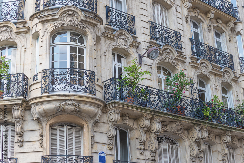 Beautiful parisian residential building with carved balconies decorated by plant