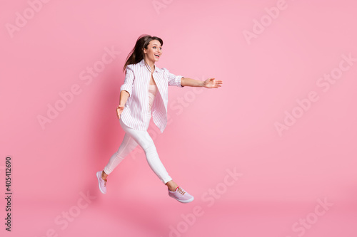 Full length photo of funny young lady wear casual white outfit jumping catching empty space isolated pastel pink color background © deagreez