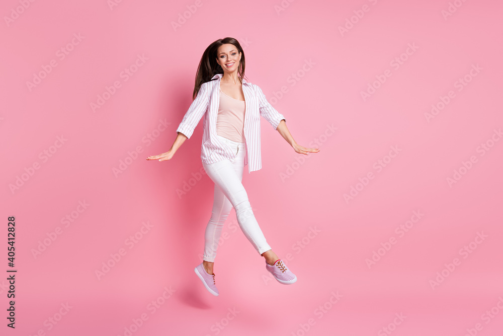 Full length photo of carefree cute young woman dressed casual white clothes isolated pastel pink color background
