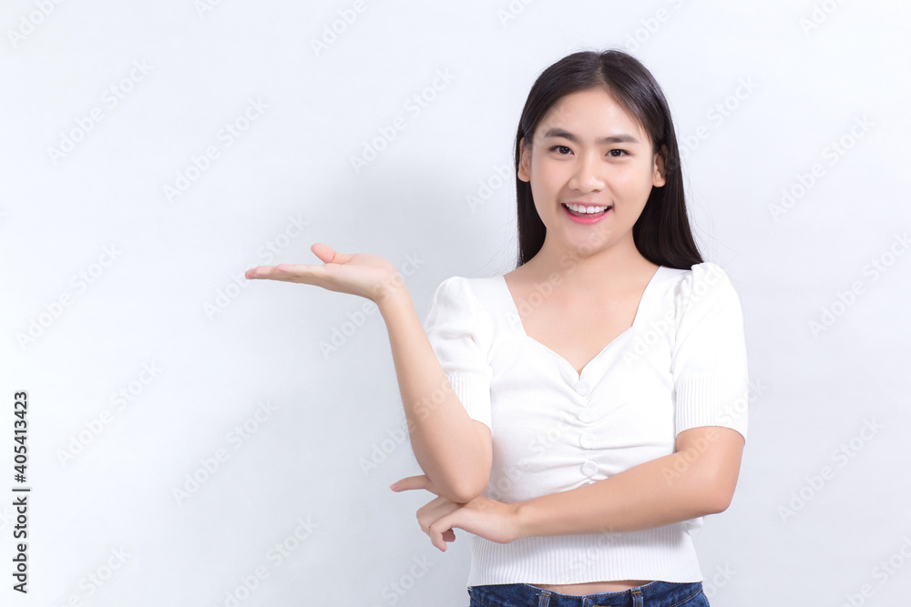 Asian girl with black long hair wearing a white shirt and pretty smiling is present product on white background. Asian girl with black long hair wearing a white shirt and pretty smiling is present product on white background.