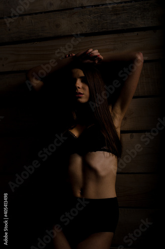 beautiful sexy girl in a black bathing suit on a background of polished boards