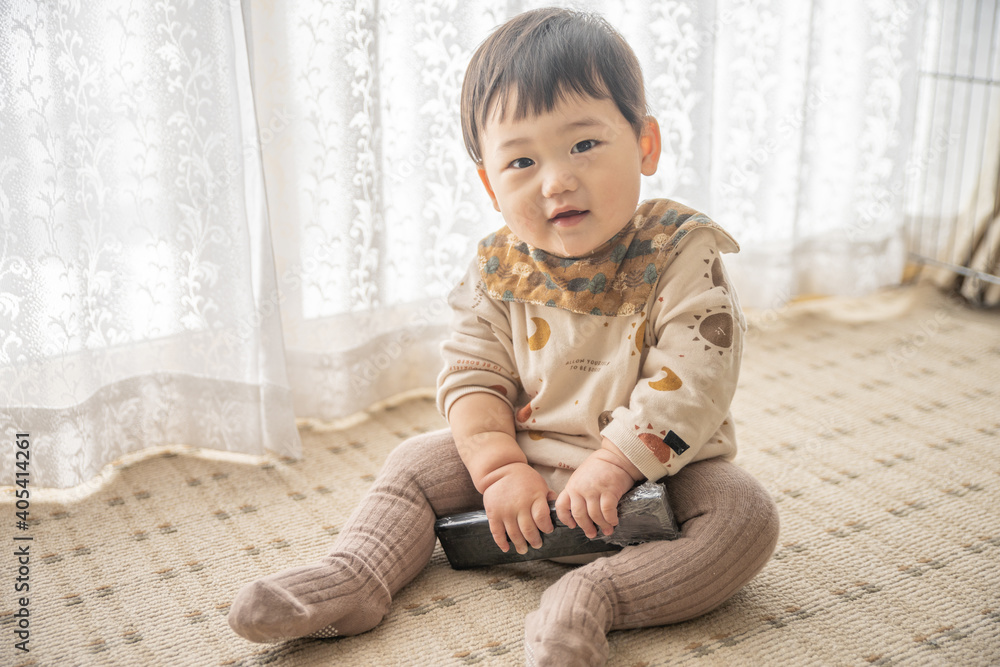 リビングでリモコンで遊ぶ赤ちゃん リビングでリモコンで遊ぶ赤ちゃん