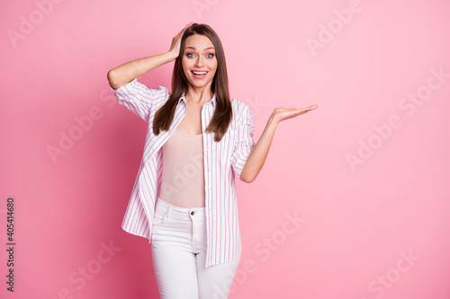 Photo of young amazed shocked smiling woman girl hold hand proposition recommend isolated on pink color background © deagreez