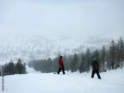 Landscape view of skiers and snowboarders on the slopes of a ski resort on a foggy day