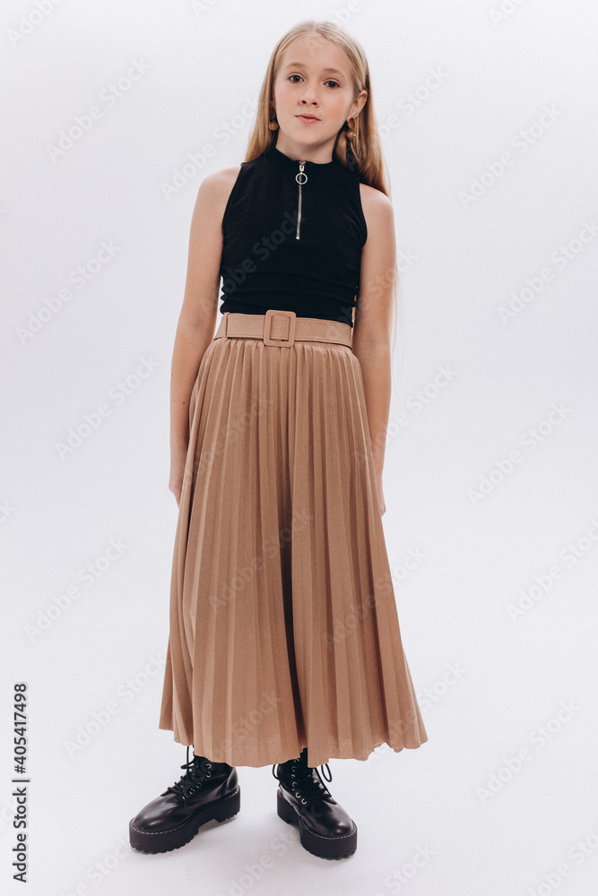 Fototapeta premium Fashion girl portrait. Modern teen blondie girl in stylish elegant clothes posing on white background