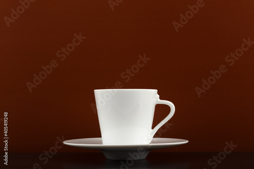 White ceramic cup of coffee or chocolate on black table against dark brown background with copy space
