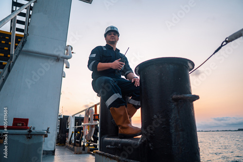 Marine Deck Officer or Chief mate on deck of offshore vessel or ship , wearing PPE personal protective equipment - helmet, coverall. Ship is on background photo