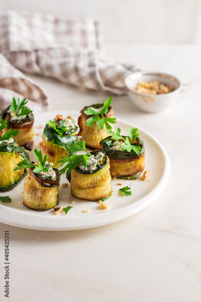 Roasted zucchini rolls stuffed with cheese on white plate Roasted zucchini rolls stuffed with cheese on white plate