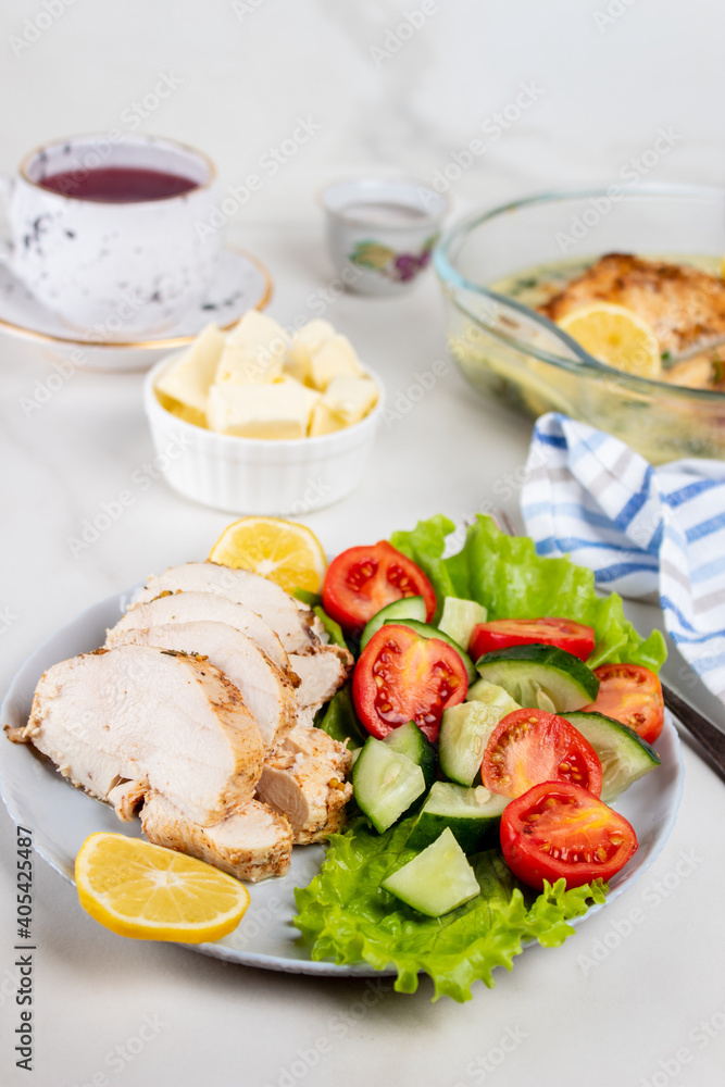 Chicken breasts with lemon sauce. Sliced chicken and fresh vegetable salad.