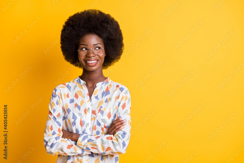 Photo of cute sweet dark skin lady dressed casual outfit glasses arms folded looking empty space isolated yellow color background Photo of cute sweet dark skin lady dressed casual outfit glasses arms folded looking empty space isolated yellow color background