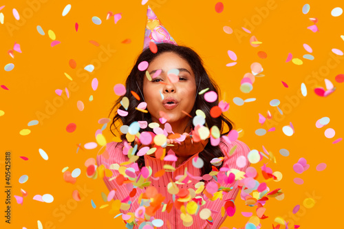 happy birthday! cheerful funny ethnic woman with festive confetti on yellow