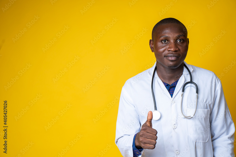 young handsome black medical doctor wearing his lab coat and hanging his stethoscope on his neck and giving thumbs up young handsome black medical doctor wearing his lab coat and hanging his stethoscope on his neck and giving thumbs up