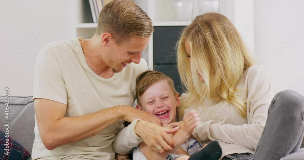 Affectionate caucasian father and mother tickling little adorable child son having fun laughing relaxing on sofa, polish parents playing with small kid boy bonding cuddling together at home. Affectionate caucasian father and mother tickling little adorable child son having fun laughing relaxing on sofa, polish parents playing with small kid boy bonding cuddling together at home.