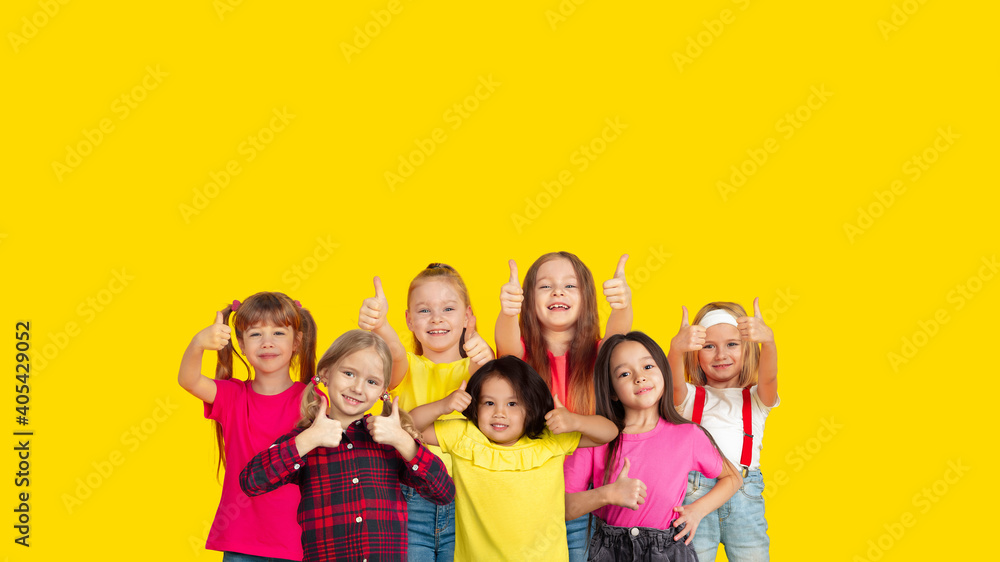 Thumbs up. Portrait of little caucasian children gesturing isolated on yellow studio background with copyspace. Cheerful kid models. Concept of human emotions, facial expression, sales, ad, childhood. Thumbs up. Portrait of little caucasian children gesturing isolated on yellow studio background with copyspace. Cheerful kid models. Concept of human emotions, facial expression, sales, ad, childhood.