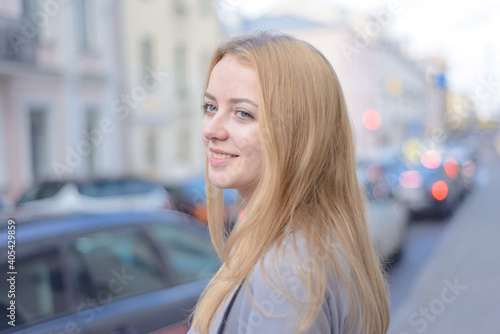 smiling stylish girl with red hair on a city street