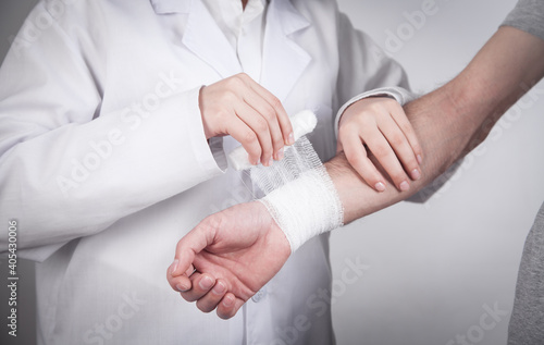 Caucasian doctor putting bandage on patient hand.