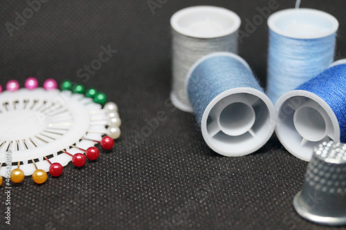threads , needles, thimbles means for sewing a hobby of needlework on a black background horizontal macro photo