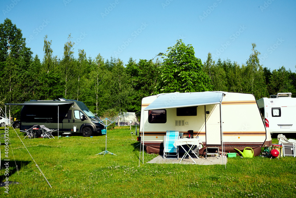 Schöner Campingplatz in der Natur mit Wohnwagen und Wohnmobile und blauem Himmel Schöner Campingplatz in der Natur mit Wohnwagen und Wohnmobile und blauem Himmel