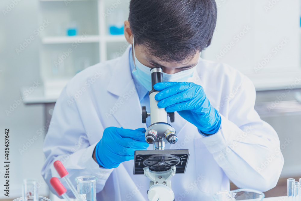 Male Scientist look into Microscope research in science laboratory. Asian scientist looking equipment laboratory chemistry labs. Covid-19 coronavirus biochemistry research experiment vaccine concept Male Scientist look into Microscope research in science laboratory. Asian scientist looking equipment laboratory chemistry labs. Covid-19 coronavirus biochemistry research experiment vaccine concept