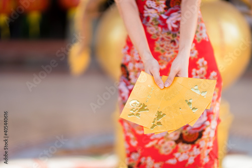 Close-up of woman wearing red traditional Chinese cheongsam decoration holding yellow envelopes in hand for Chinese New Year Festival at Chinese shrine in Thailand