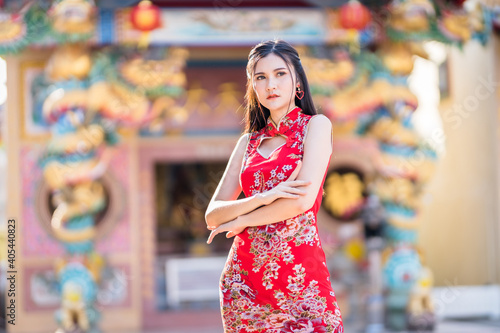 Portrait beautiful smiles Asian young woman wearing red traditional Chinese cheongsam decoration for Chinese New Year Festival at Chinese shrine in Thailand
