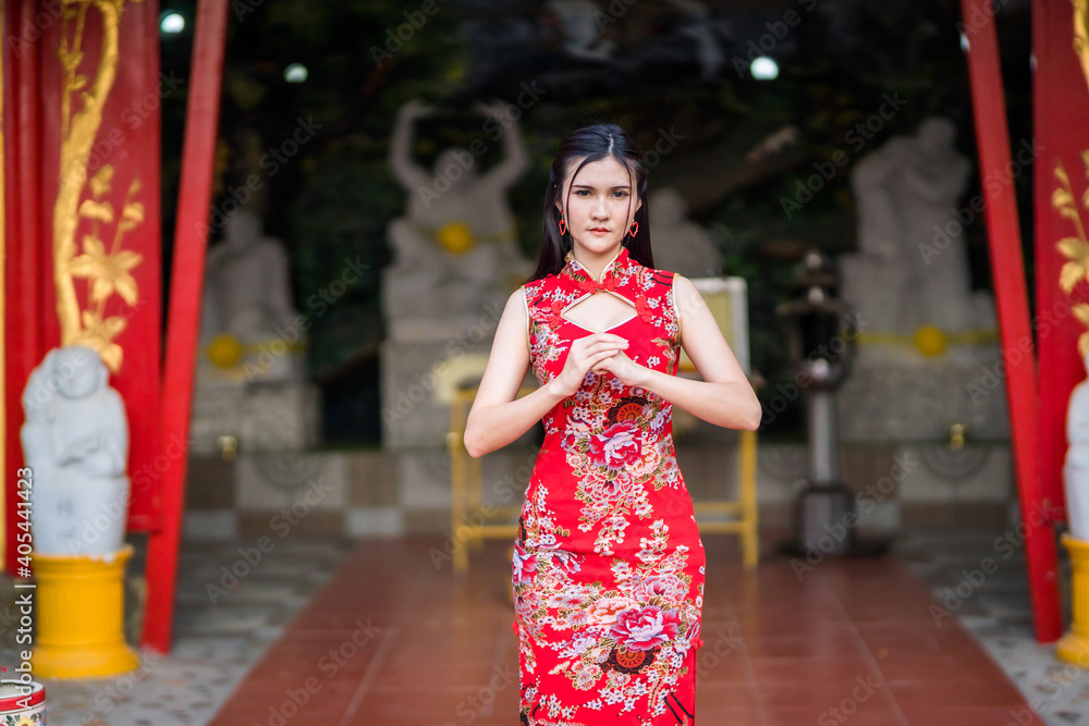 Portrait beautiful smiles Asian young woman wearing red traditional Chinese cheongsam decoration for Chinese New Year Festival at Chinese shrine in Thailand Portrait beautiful smiles Asian young woman wearing red traditional Chinese cheongsam decoration for Chinese New Year Festival at Chinese shrine in Thailand